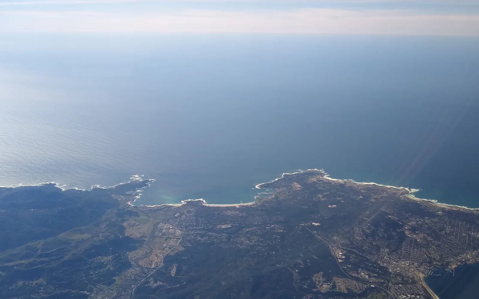 Aerial view of the Monterey Peninsula showing the curved coastline and developed residential areas along Monterey Bay